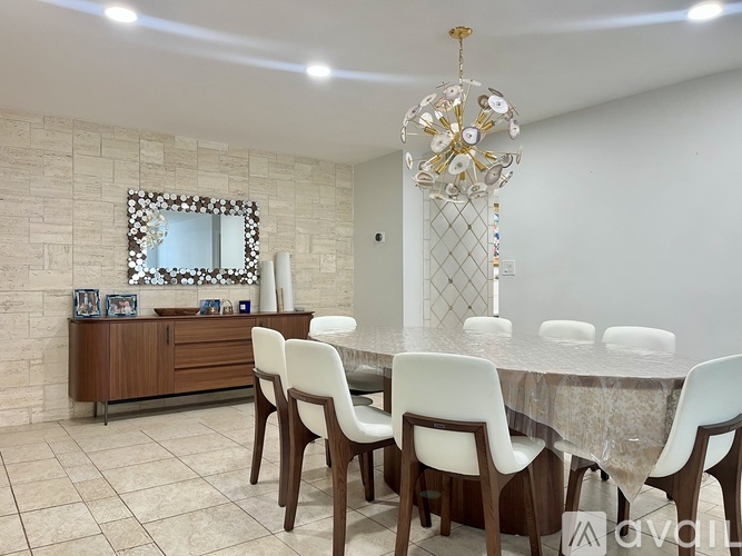 A dining room with a table, chairs, and a chandelier.