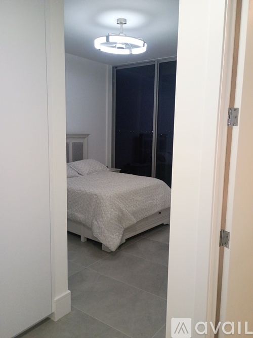 A bedroom with a bed, a ceiling light, and a door.