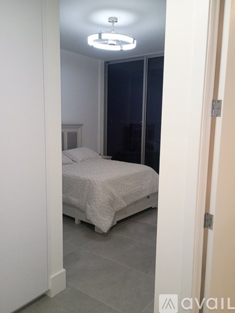 A bedroom with a bed, a ceiling light, and a door.
