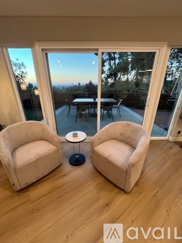 Two chairs are placed in front of a large window with a view of a dining area outside.