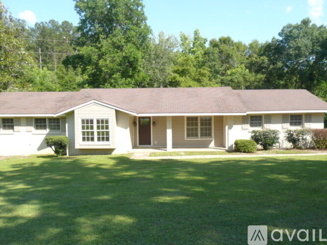 A house with a brown roof and a lawn in front of it.
