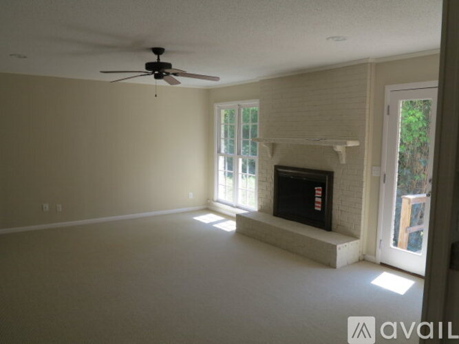 A living room with a fireplace and a ceiling fan.