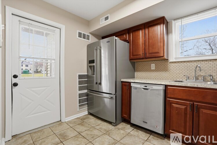 A kitchen with a white door, a fridge, a dishwasher, and a sink.