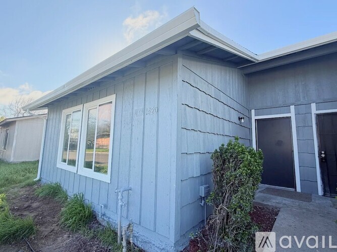 A house with a grey siding and a small window is for sale.