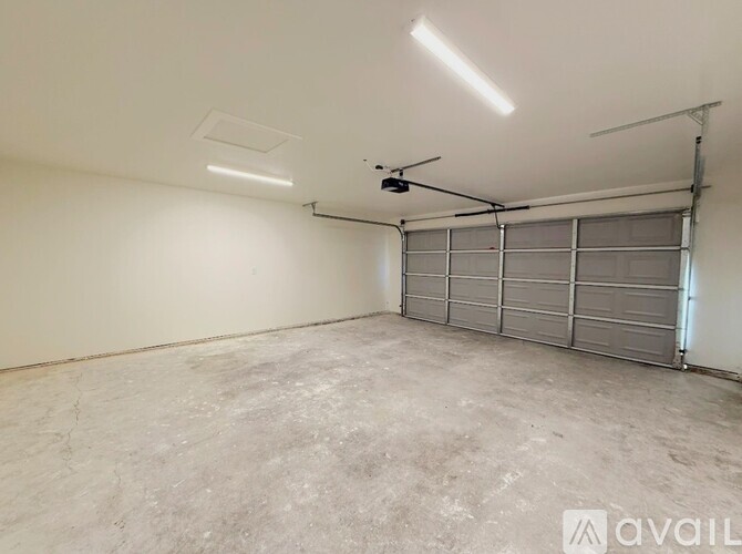 A spacious garage with a concrete floor and a grey roller shutter door.