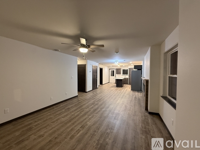A spacious room with wooden flooring and a ceiling fan.