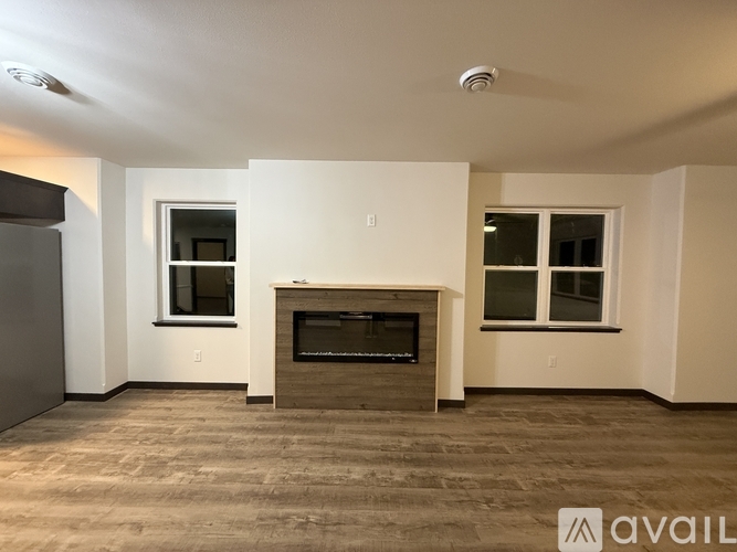 A living room with a fireplace and two windows.