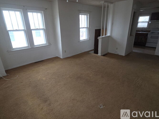 A room with a carpeted floor and two windows.