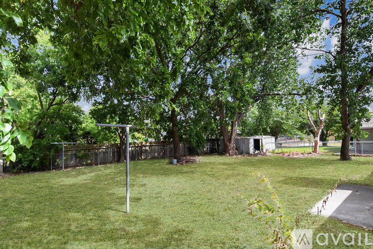 A backyard with a green lawn and trees.