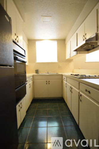 A kitchen with white cabinets and a black refrigerator.
