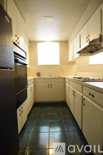A kitchen with white cabinets and a black refrigerator.