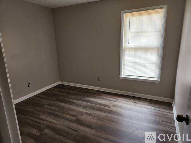 A room with a window and wooden flooring.