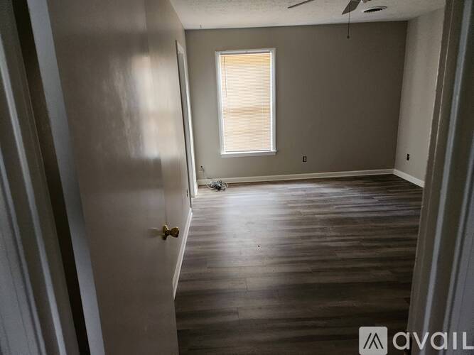 A room with wooden floors and a window letting in sunlight.