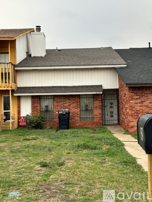 A house with a red brick wall and a black mailbox.