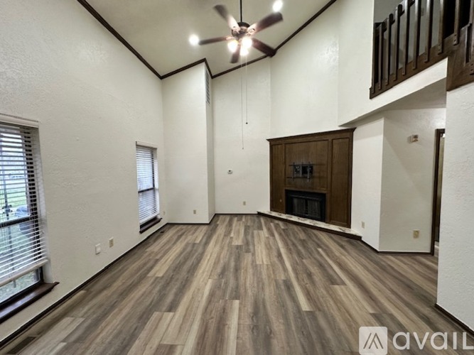 A spacious room with wooden flooring and a ceiling fan.
