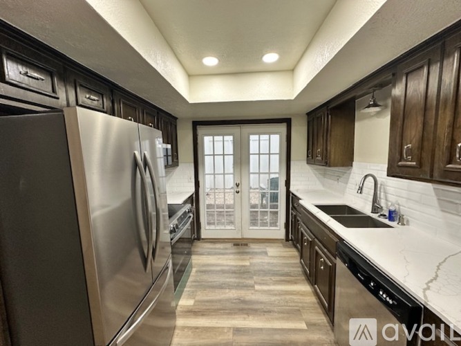 A modern kitchen with dark wood cabinets and stainless steel appliances.