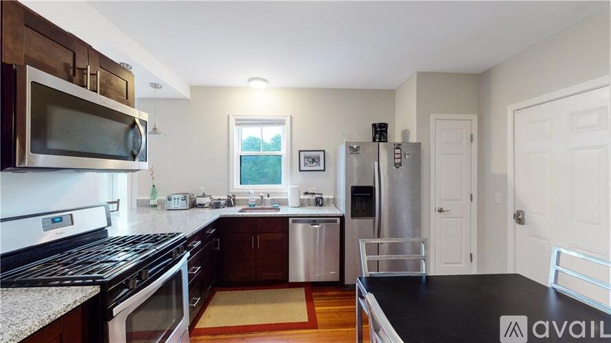 A kitchen with a black counter top and stainless steel appliances.