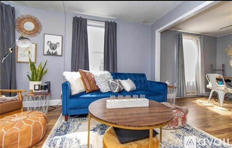 A living room with a blue couch, a wooden coffee table, and a white lamp.