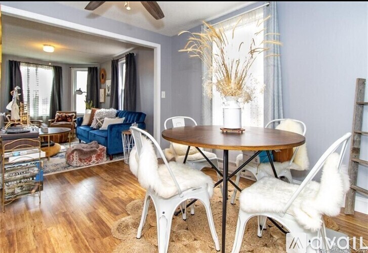 A dining room with a round table and white chairs.