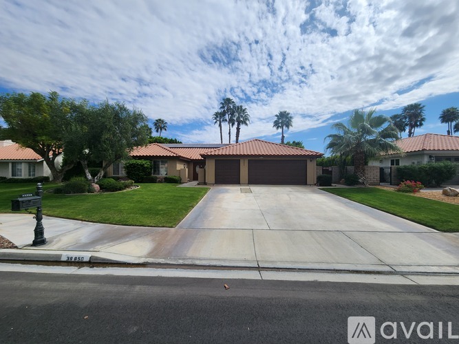 A house with a driveway and palm trees in the background.
