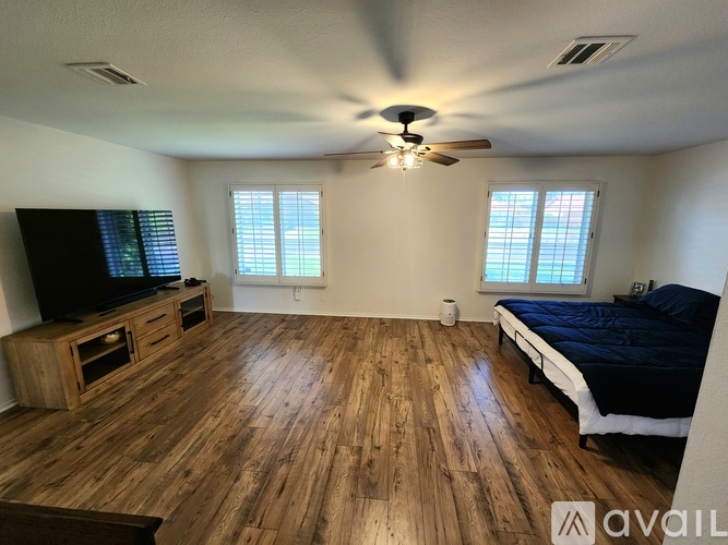 A bedroom with a bed, a television, and a wooden floor.