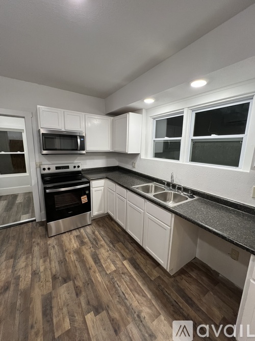 A kitchen with white cabinets and a black countertop.