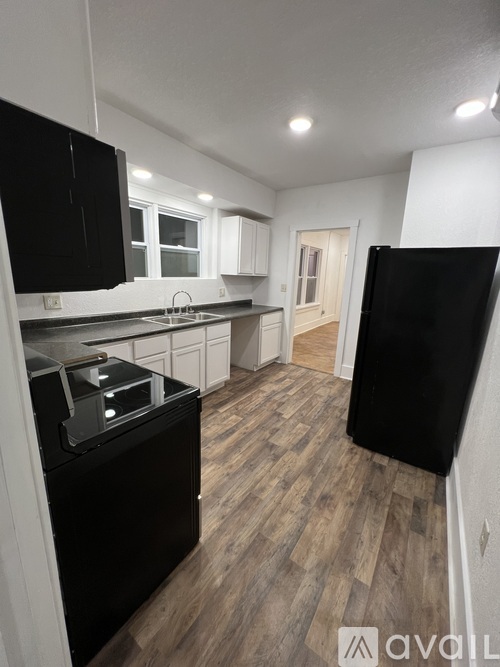 A kitchen with black appliances and wooden floors.