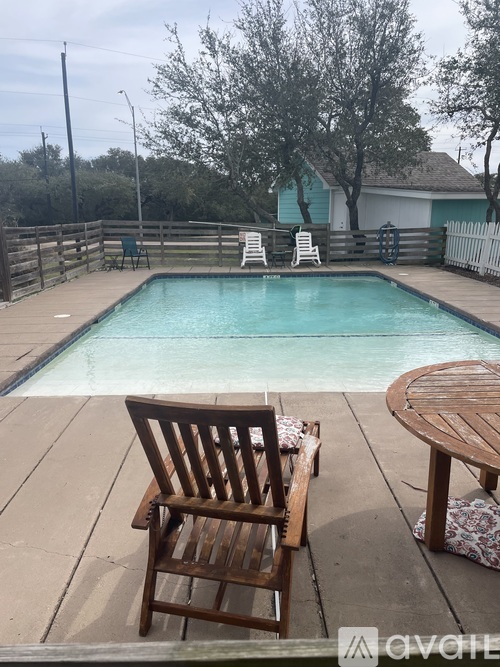 A wooden chair is in the foreground of a pool area.