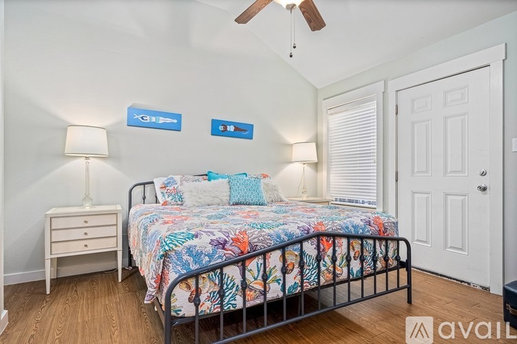 A bedroom with a floral bedspread and a ceiling fan.