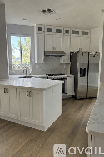 A kitchen with white cabinets and a marble countertop.