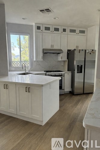 A kitchen with white cabinets and a marble countertop.