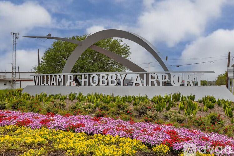 A sign for William R. Hobby Airport is displayed in front of flowers.