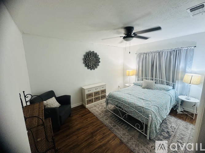 A bedroom with a bed, chair, and ceiling fan.