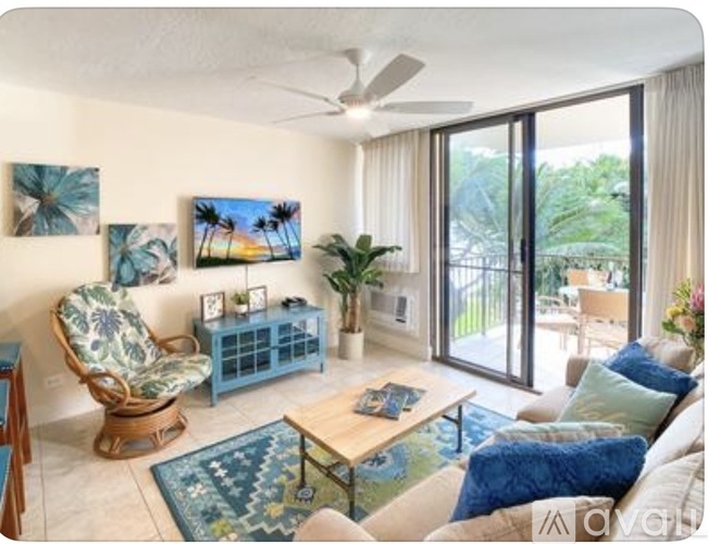 A living room with a blue chair and a painting of a beach scene on the wall.