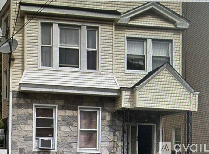 A house with a stone wall and a window with a curtain.