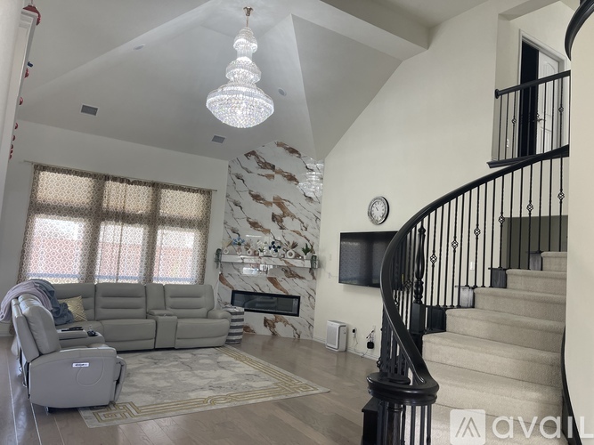 A living room with a grey sofa and a staircase with a black railing.