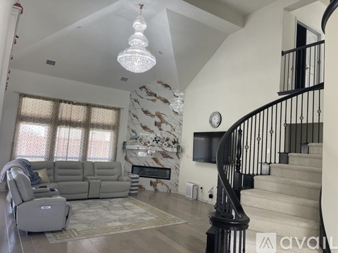A living room with a grey sofa and a staircase with a black railing.
