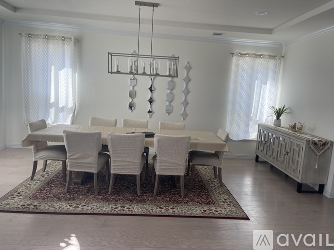A dining room with a large table and chairs.