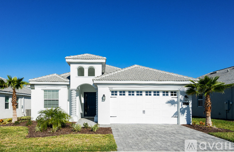 A white house with a grey roof and a black garage door.