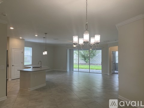 A spacious kitchen with a large island and a chandelier hanging from the ceiling.