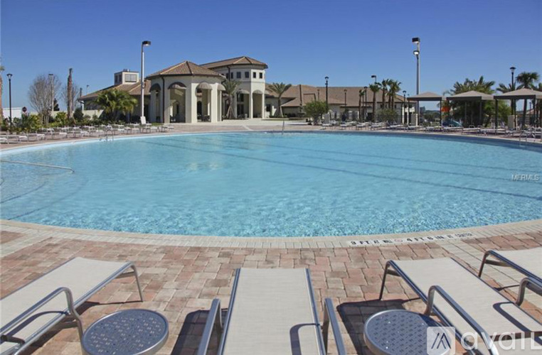 A large swimming pool with lounge chairs and a building in the background.