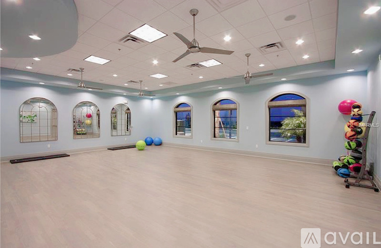 A spacious room with a wooden floor and a ceiling fan.
