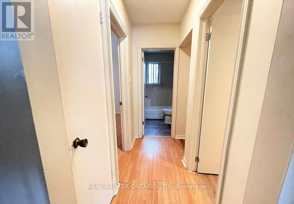 A hallway with a door on the left and a bedroom at the end.