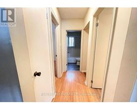 A hallway with a door on the left and a bedroom at the end.