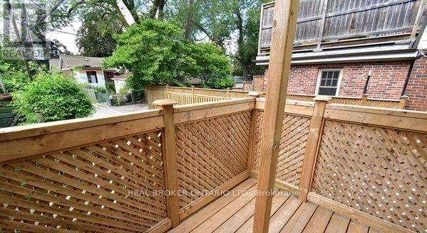 A wooden deck with lattice work and a tree in the background.