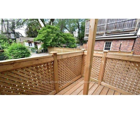 A wooden deck with lattice work and a tree in the background.