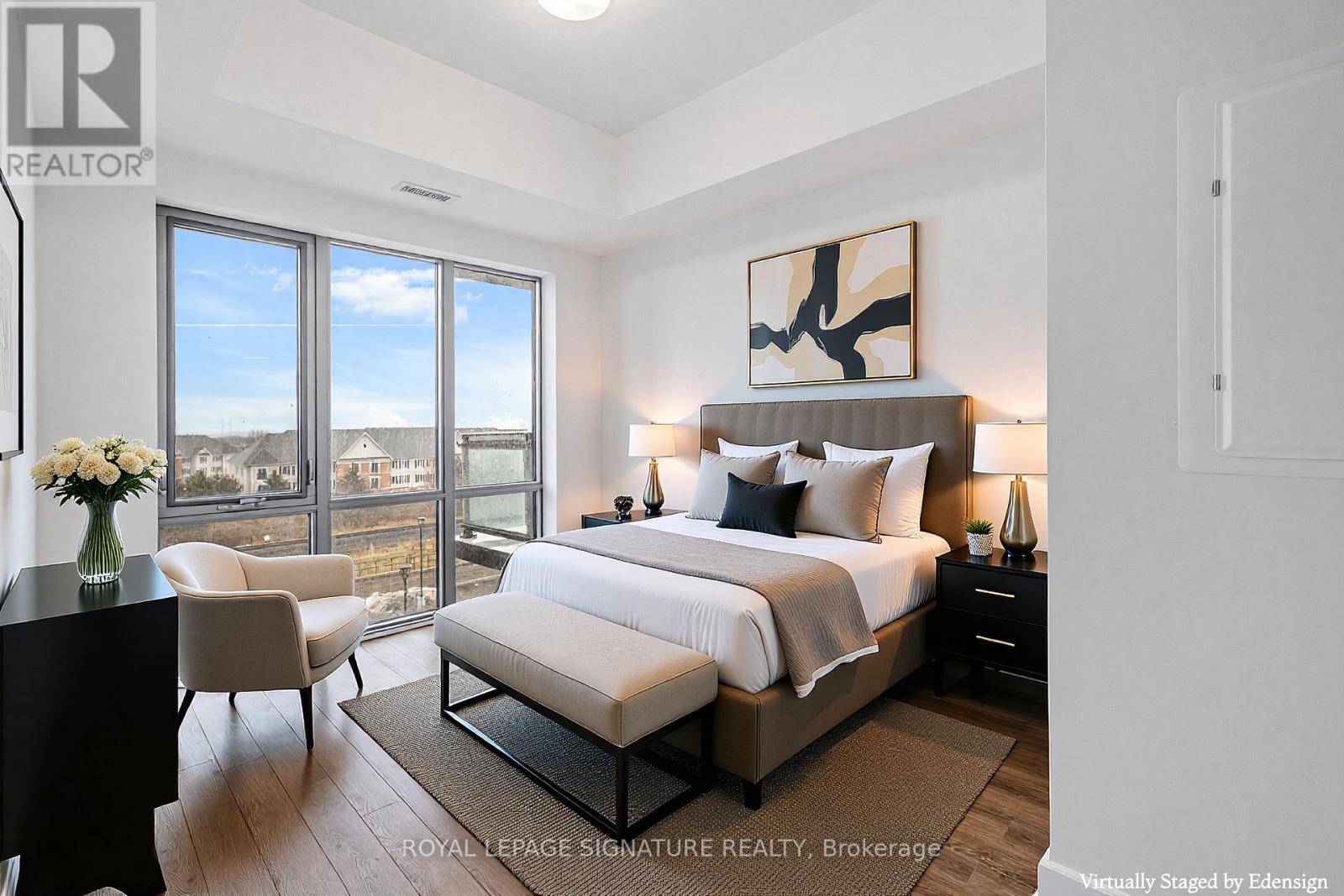A bedroom with a large bed, a chair, and a painting on the wall.