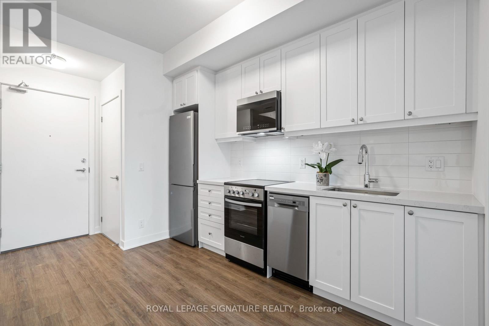 A white kitchen with a refrigerator, oven, and microwave.