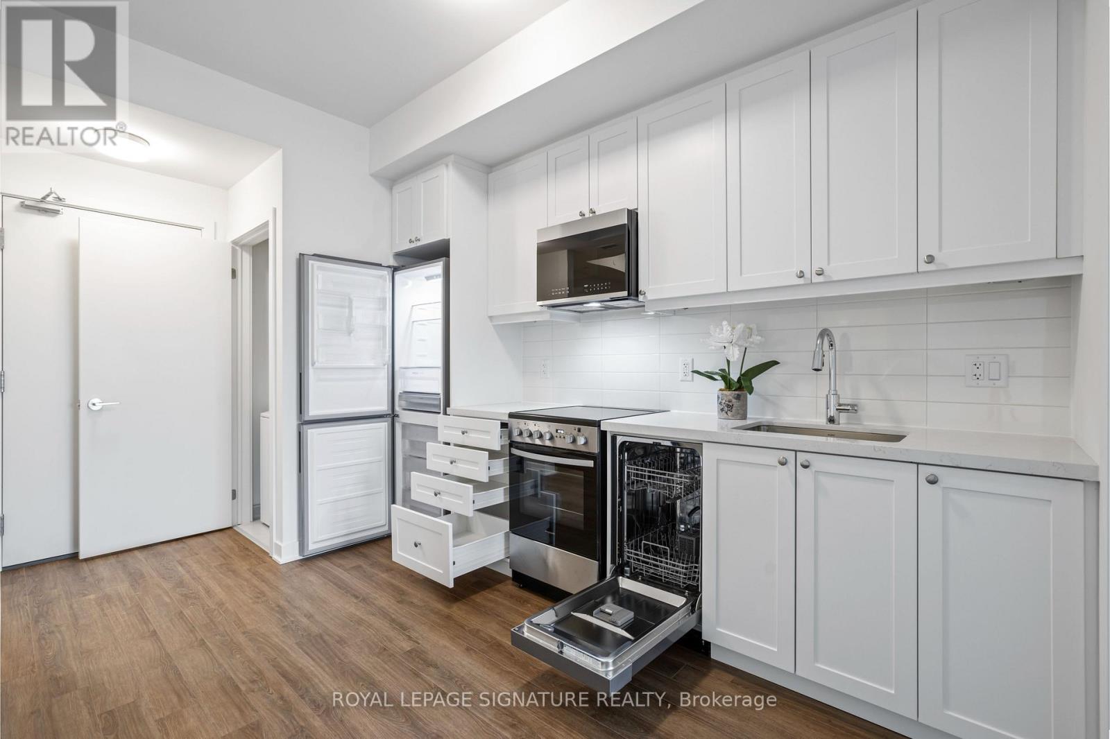 A kitchen with white cabinets and a fridge with the door open.