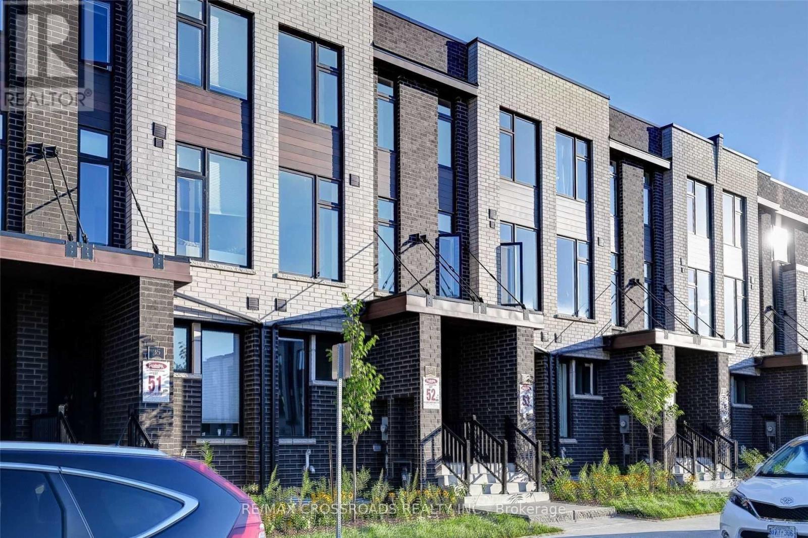 A row of modern townhouses with a car parked in front.